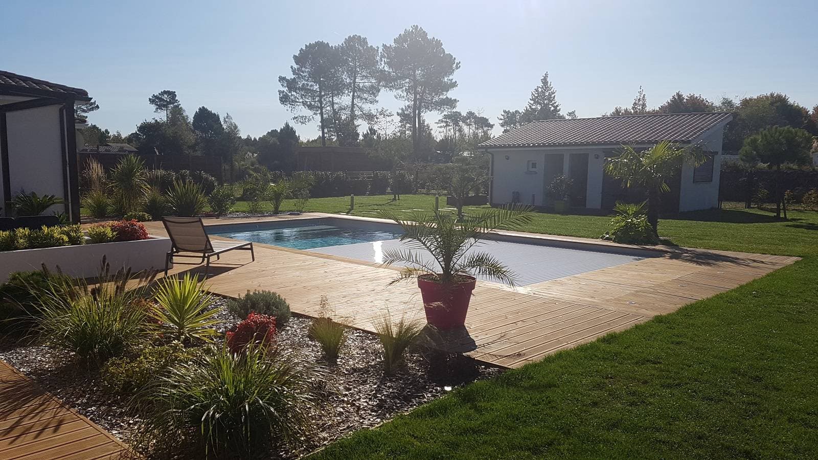 Jardin avec piscine, terrasse bois et massifs plantés réalisé par Bouleris à Soulac-sur-Mer
